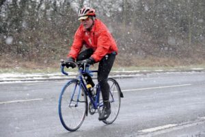 man riding bicycle during snow fall