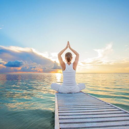 woman sitting at edge of pier in yoga pose